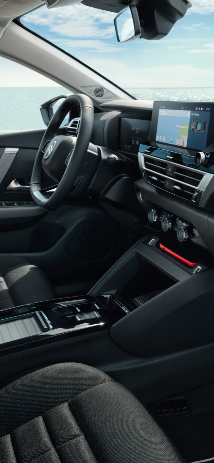 Voorcabine van de Citroën ë‑C4 X met stoelen, dashboard en uitzicht op zee door de ramen.